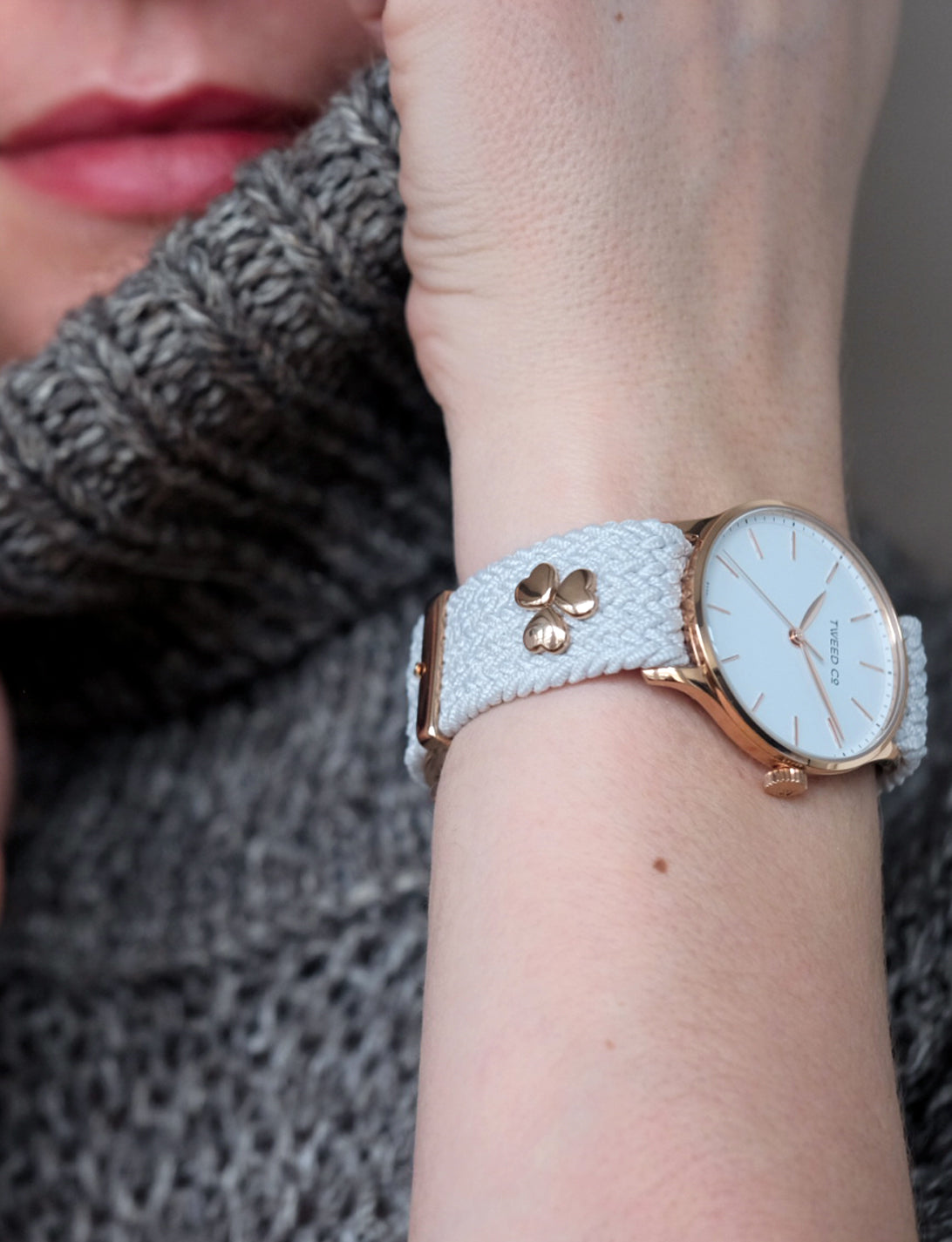 Montre Tweed Co. Kate portée au poignet, avec bracelet blanc et plusieurs charms en forme de cœur, symbole d’élégance personnalisée et d’artisanat suisse