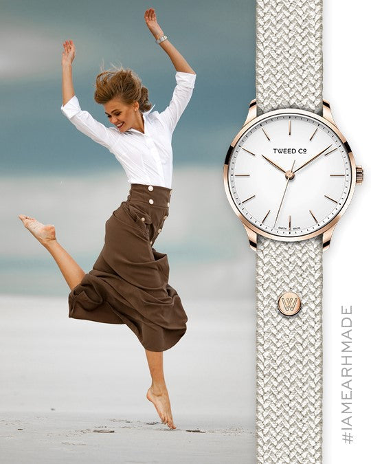 Jeune femme joyeuse en train de sauter, portant une montre Kate en acier avec bracelet blanc en gros plan