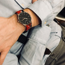 Duncan watch worn by a man, red-black strap visible on a light-coloured shirt